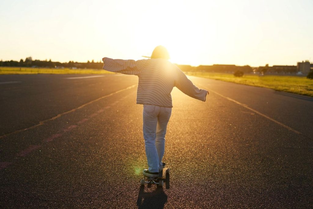 A young woman skating towards the light of the setting sun.